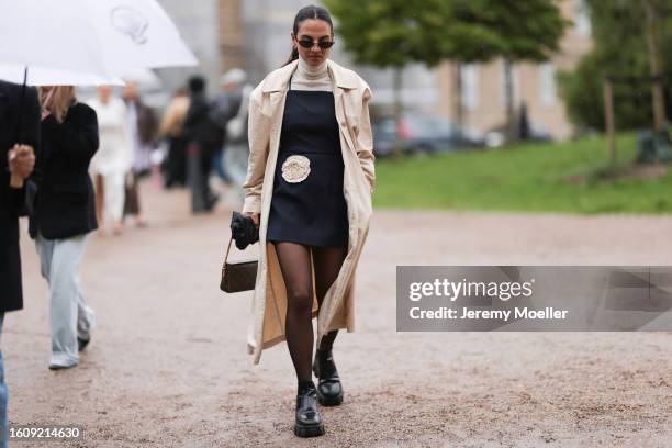 Anna Winter seen wearing black Balenciaga sunnies, The Garment beige turtle neck, little black dress with beige flower detail, beige trench coat, see...