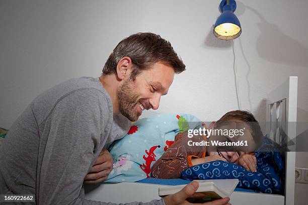 germany, berlin, father reading book while son sleeping - bedtime story book stock pictures, royalty-free photos & images