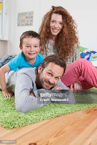 germany, berlin, family lying on floor, smiling, portrait - posen stockfoto's en -beelden