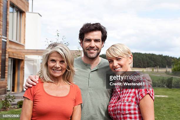 germany, bavaria, nuremberg, family in front of house, smiling - bavarian man in front of house stockfoto's en -beelden