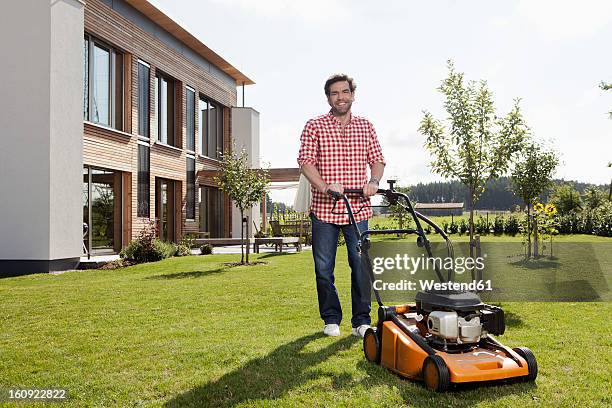 germany, bavaria, nuremberg, mature man with lawn mower in garden - lawnmower stock-fotos und bilder