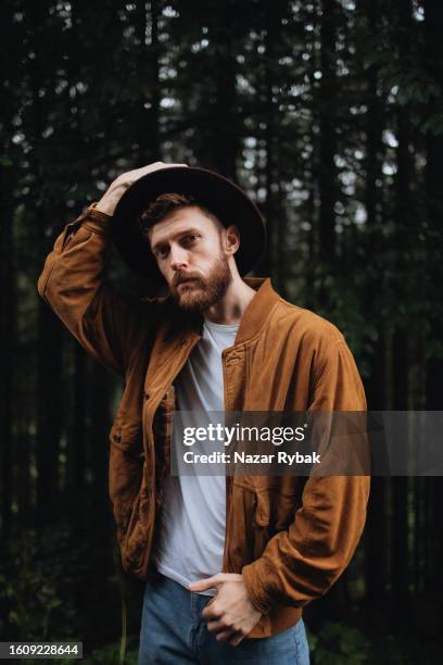 the portrait of a stylish handsome man in a hat in the forest tree background - a fall from grace 個照片及圖片檔