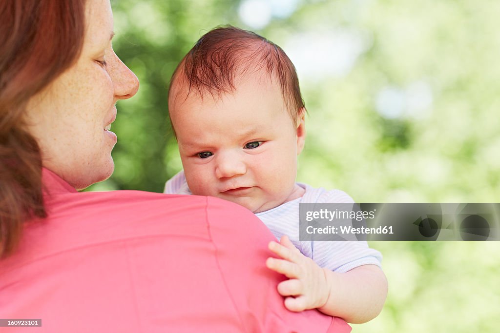 Germany, Cologne, Mother carrying her baby boy, smiling