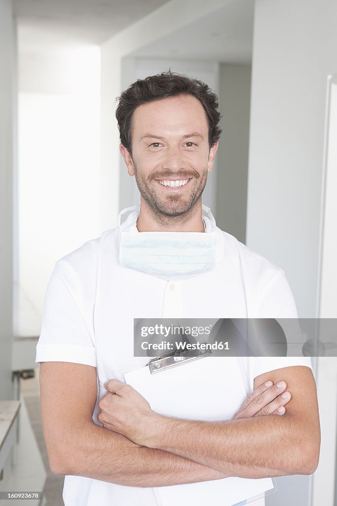 Germany, Dentist holding clip board, smiling, portrait
