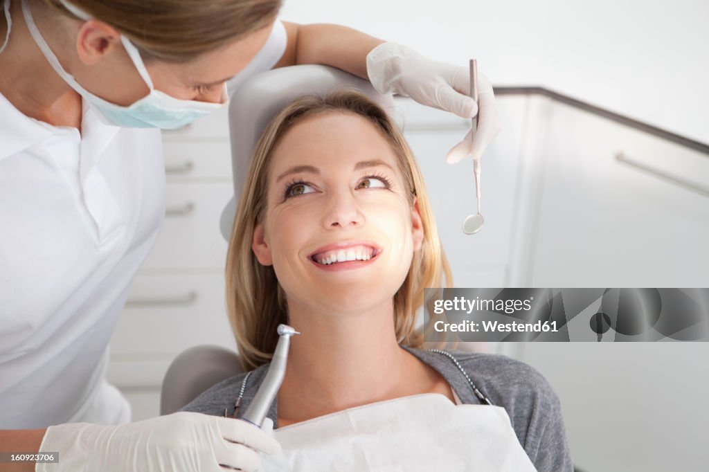 Germany, Young woman getting her teeth examined by dentist