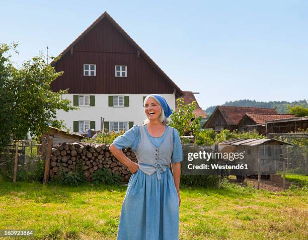 germany, bavaria, mature woman standing in front of farm - bavarian man in front of house stock-fotos und bilder