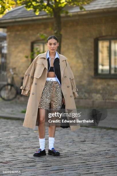 Guest wears a silver rhinestones necklace, a pale blue shirt, a black blazer jacket, a beige long trench coat, white panties, beige and black leopard...