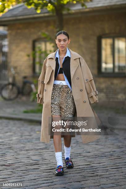 Guest wears a silver rhinestones necklace, a pale blue shirt, a black blazer jacket, a beige long trench coat, white panties, beige and black leopard...