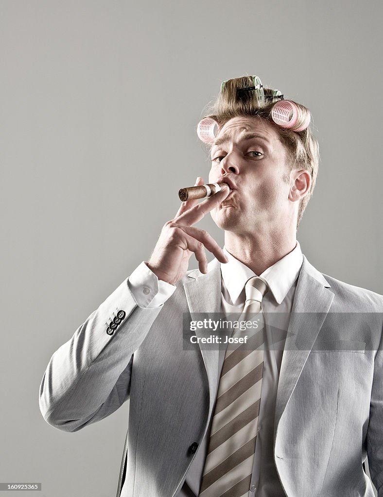 Portrait of businessman with curlers in hair and smoking cigar