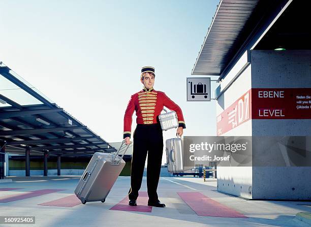 portrait of bellboy carrying suitcases - bellhop stockfoto's en -beelden