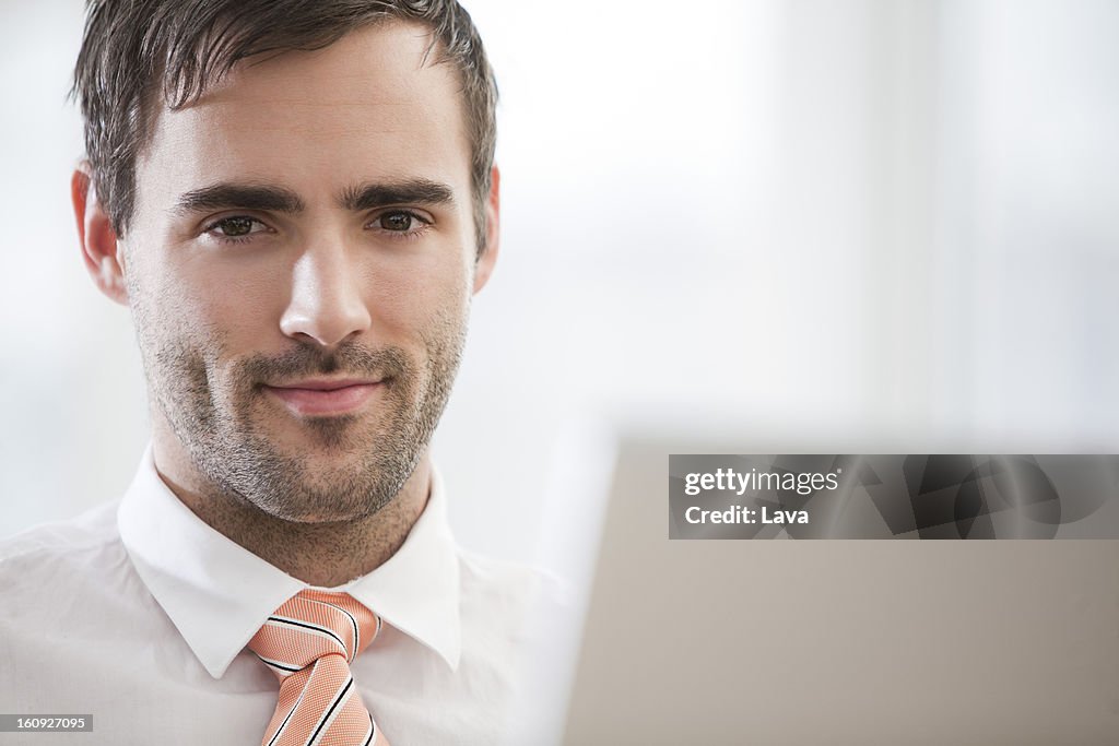 Portrait of young businessman behand computer