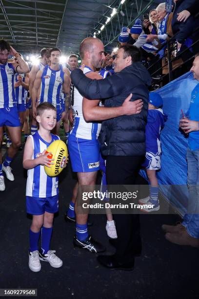 Ben Cunnington of the Kangaroos walks from the ground with his children and shares an embrace with former coach Brad Scott after his final game, the...