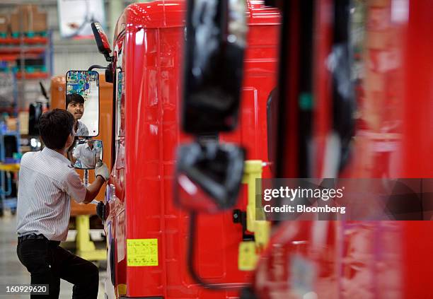 An employee inspects side mirrors on the assembly line for the Mahindra & Mahindra Ltd. Navistar truck at the company's factory in Chakan,...