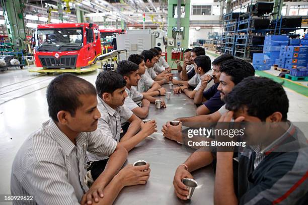 Employees sit at a bench as they take a break at the Mahindra & Mahindra Ltd. Factory in Chakan, Maharashtra, India, on Wednesday, Feb. 6, 2013....