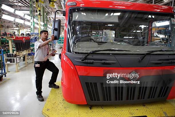 An employee inspects a side mirror on the assembly line for the Mahindra & Mahindra Ltd. Navistar truck at the company's factory in Chakan,...