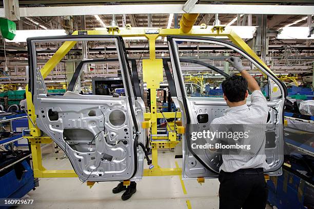 Employees assemble vehicle doors on the assembly line for the Mahindra & Mahindra Ltd. XUV 500 sport utility vehicle at the company's factory in...