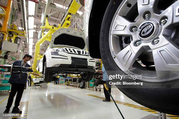 Employees install wheel components on the assembly line for the Mahindra & Mahindra Ltd. XUV 500 sport utility vehicle at the company's factory in...