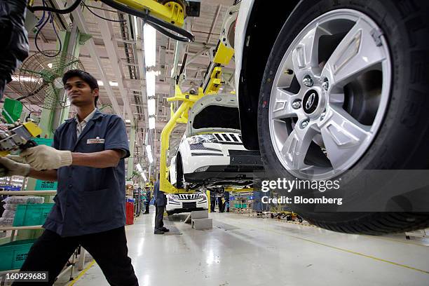 An employee walks past vehicles on the assembly line for the Mahindra & Mahindra Ltd. XUV 500 sport utility vehicle at the company's factory in...