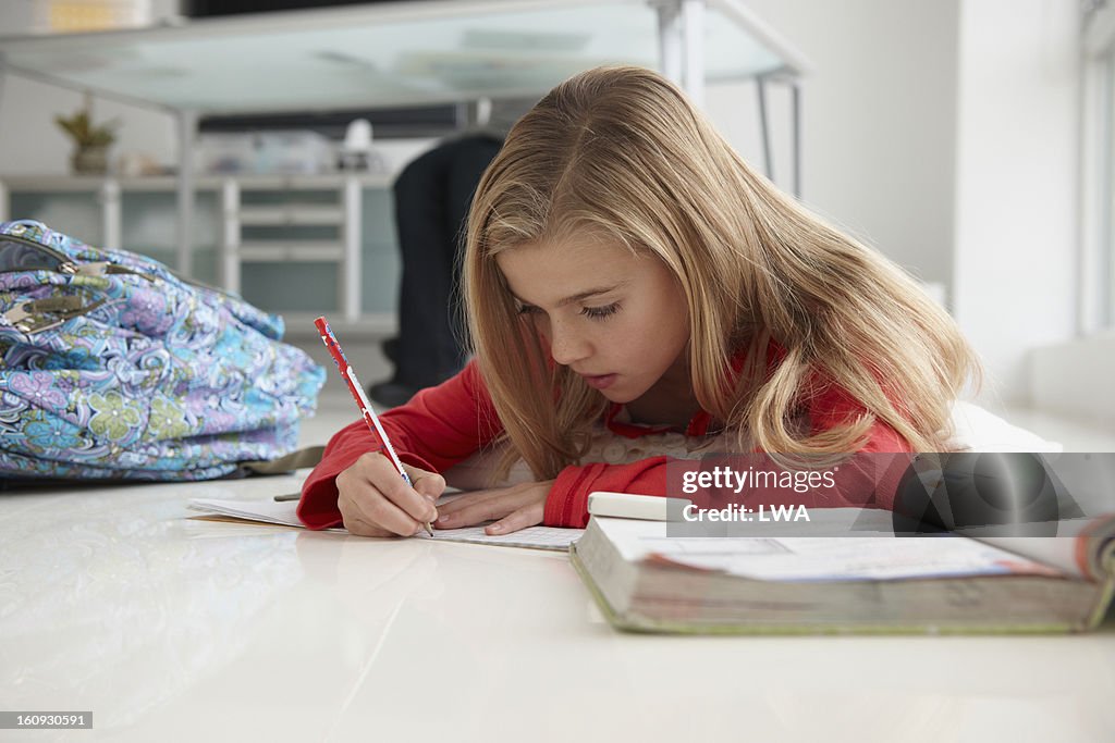 Young girl doing homework on floor of home office