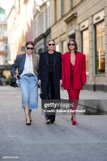 Annabel Rosendahl wears a white shirt, a bicolored gray and brown blazer jacket, a black shiny leather nailed / studded belt, a pale blue faded denim...