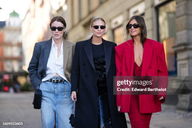 Annabel Rosendahl wears a white shirt, a bicolored gray and brown blazer jacket, a black shiny leather nailed / studded belt, a pale blue faded denim...