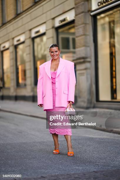 Janka Polliani wears rhinestones pendant earrings from Chanel, a pale pink oversized blazer jacket, a pink embossed ruffled midi dress, a pale pink...