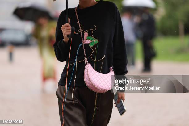 Katya Tolstova seen wearing Burberry umbrella, black and golden asymmetric sunnies, yellow see through earrings, distressed black sweater with...