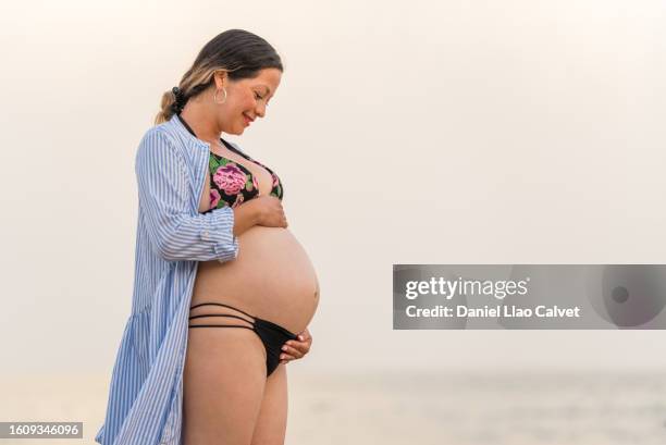 mid adult pregnant woman standing on beach - mujer playa stock pictures, royalty-free photos & images