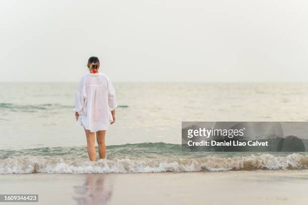 woman in long white shirt walking on empty beach - mujer playa stock pictures, royalty-free photos & images