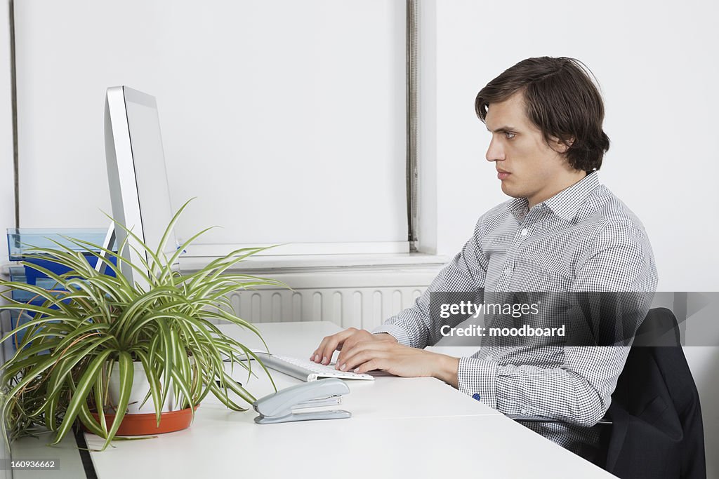 Young businessman typing at office desk