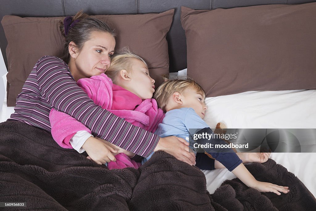 Mother lying in bed with two children