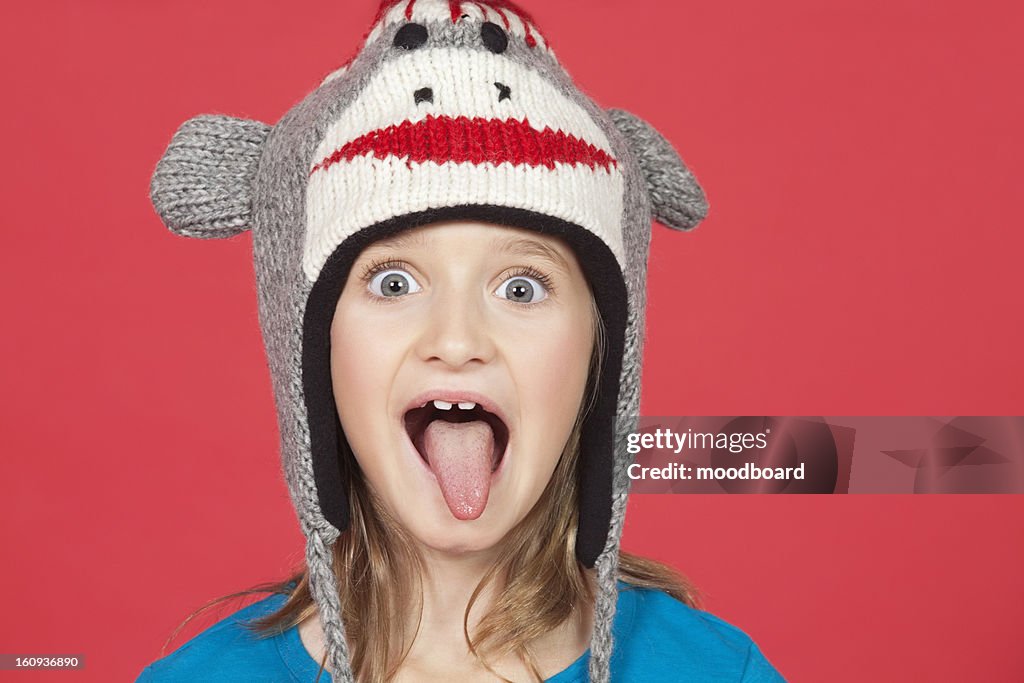Portrait of girl sticking out tongue against red background