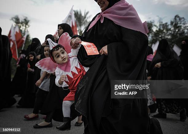 Bahraini woman holds her child as she takes part in an anti-government rally to demand reforms on February 7, 2013 in the village of Karannah, west...