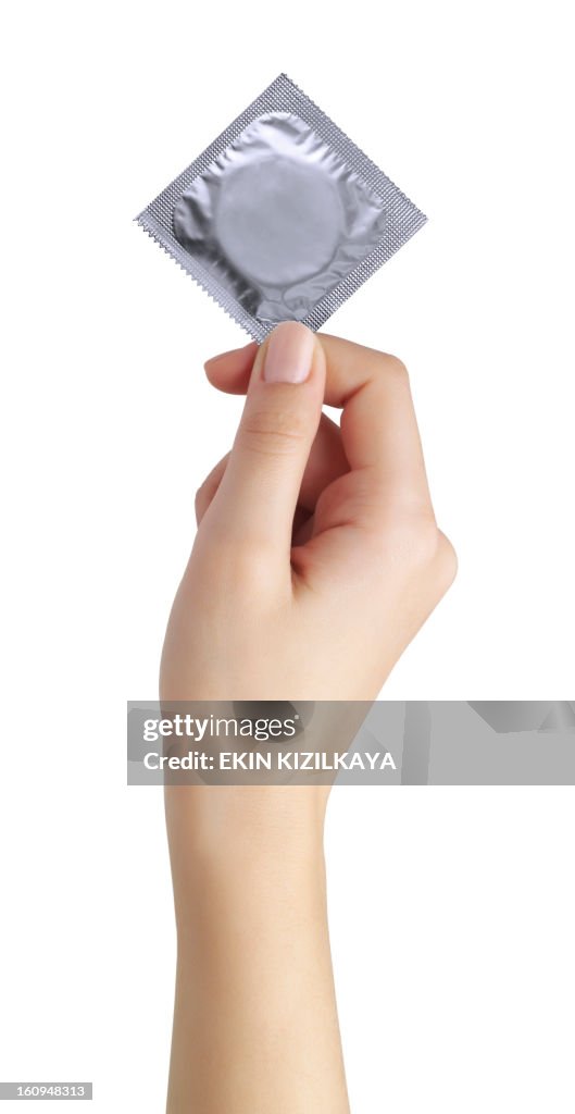 Condom in female hand isolated on a white background