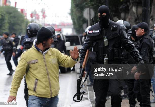 Tunisian policemen gestures to a policeman as police disperse protesters during a demonstration following the funeral of assassinated opposition...