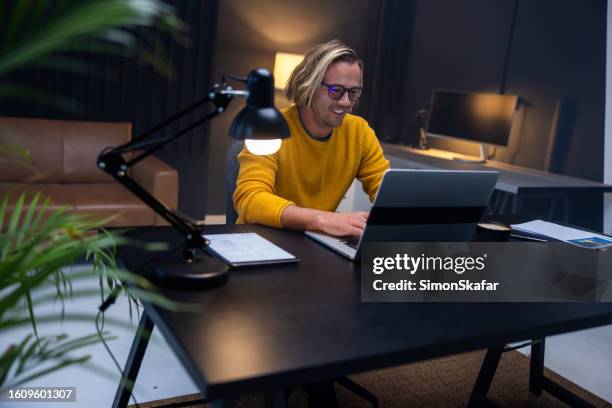 smiling businessman using laptop on desk in office - angle poise lamp stock pictures, royalty-free photos & images