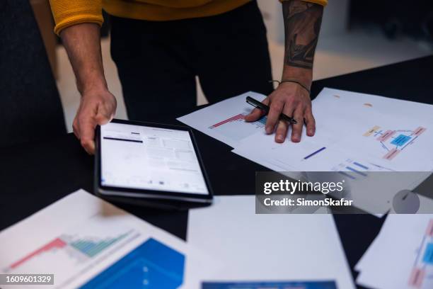 male entrepreneur with paper documents and digital tablet on desk - workflow efficiency stock pictures, royalty-free photos & images