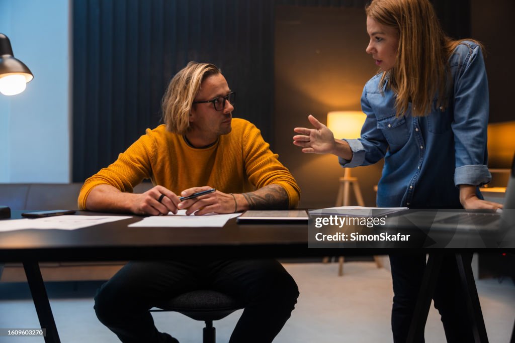 Businesswoman discussing with male colleague at desk in office
