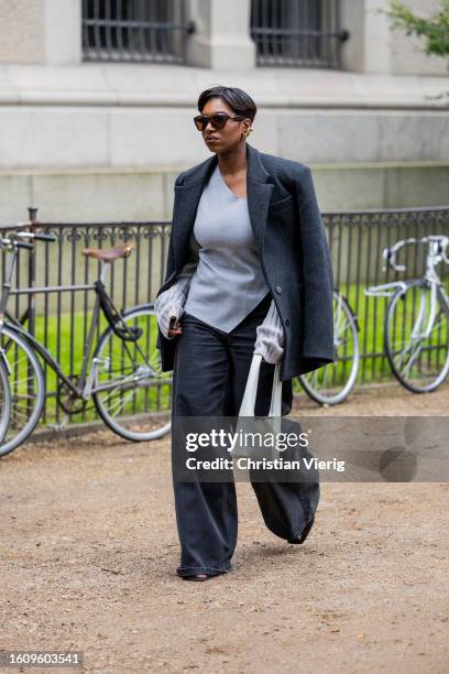 Guest wears grey blazer, denim jeans, creme white bag, grey asymmetric top outside Mark Kenly Domino Tan during the Copenhagen Fashion Week...