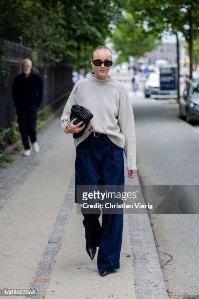 Guest wears white jumper, black bag, denim jeans outside Mark Kenly Domino Tan during the Copenhagen Fashion Week Spring/Summer 2024 on August 10,...