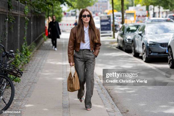 Annabel Rosendahl wears brown leather jacket, grey pants, bag outside Mark Kenly Domino Tan during the Copenhagen Fashion Week Spring/Summer 2024 on...