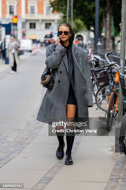 Guest wears black hoody, grey oversized coat, knee socks outside Mark Kenly Domino Tan during the Copenhagen Fashion Week Spring/Summer 2024 on...