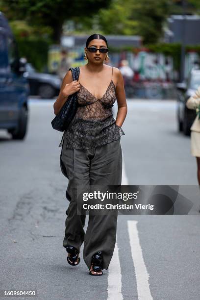 Guest wears black laced dress, grey pants outside Gestuz during the Copenhagen Fashion Week Spring/Summer 2024 on August 10, 2023 in Copenhagen,...