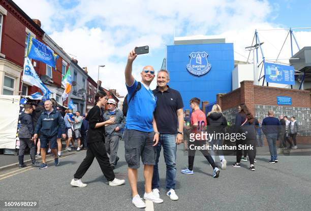 Fans of Everton pose for a selfie photograph using a mobile phone on the outside of the stadium prior to the Premier League match between Everton FC...