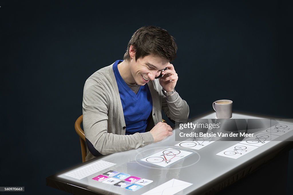 Man on phone while looking at interactive table.