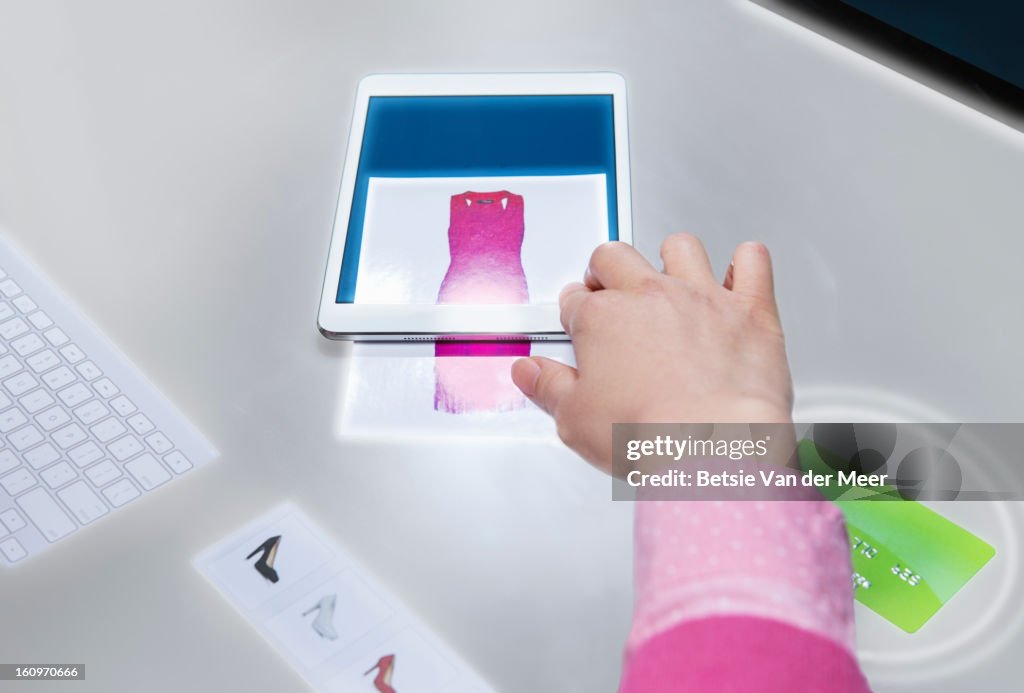 Woman swiping image from interactive table to tablet computer