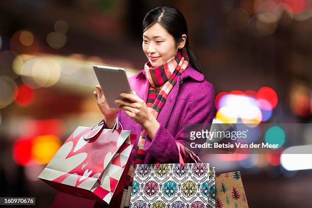 woman checking wireless device in city, - bunter mantel stock-fotos und bilder