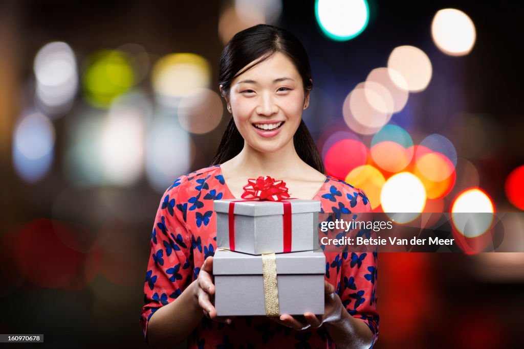 Asian woman holding presents,smiling.