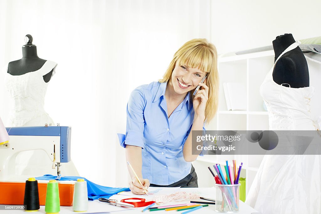 Young Woman Fashion Designer Sketching and talking on the phone.