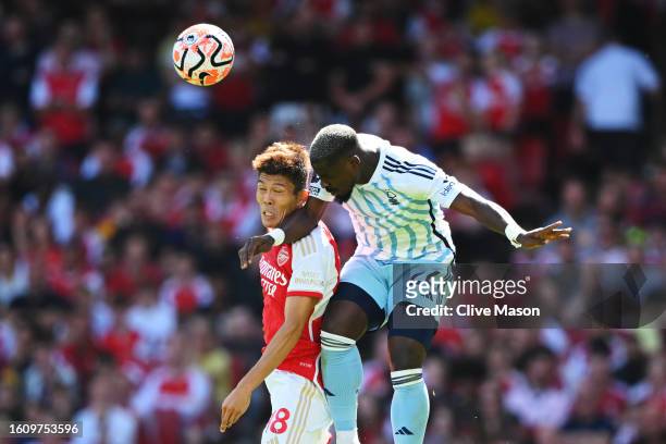 Takehiro Tomiyasu of Arsenal and Serge Aurier of Nottingham Forest battle for a header during the Premier League match between Arsenal FC and...